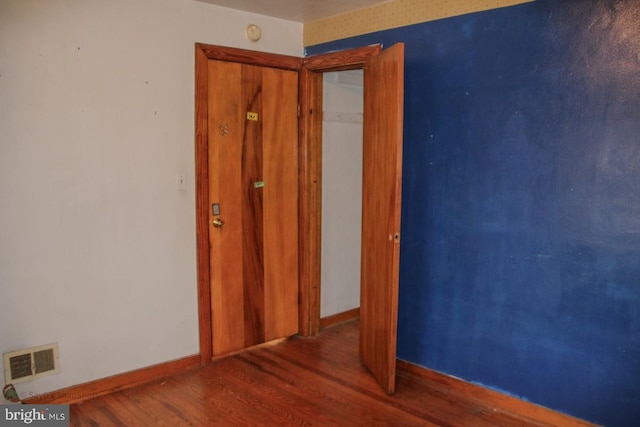 spare room with wood finished floors, visible vents, and baseboards