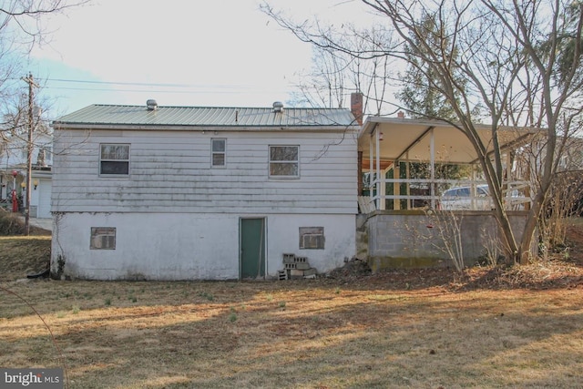 back of house with metal roof, a yard, and a chimney