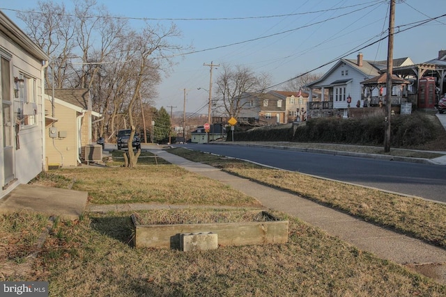 view of road featuring traffic signs, curbs, sidewalks, and a residential view