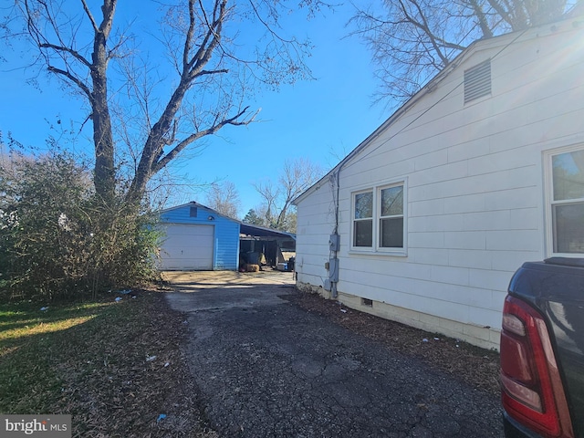 view of home's exterior featuring an outbuilding, crawl space, driveway, and a garage