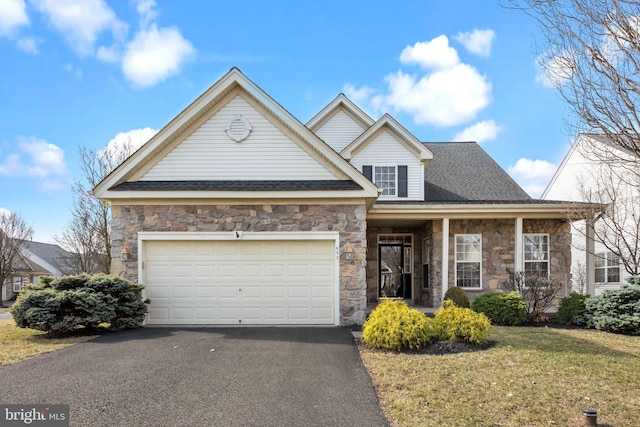 view of front of house featuring a front yard, driveway, roof with shingles, a garage, and stone siding