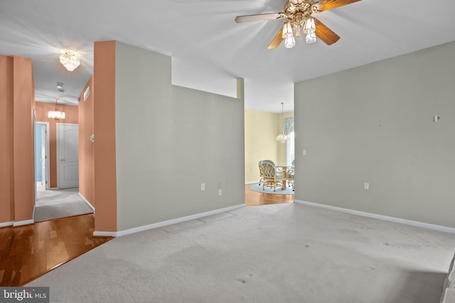 carpeted empty room featuring baseboards and ceiling fan with notable chandelier