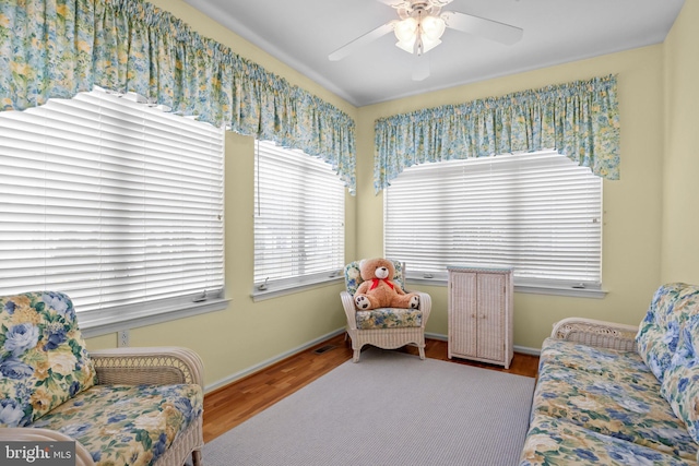 sitting room with baseboards, wood finished floors, visible vents, and ceiling fan