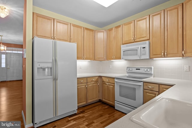 kitchen with tasteful backsplash, light brown cabinetry, dark wood finished floors, light countertops, and white appliances