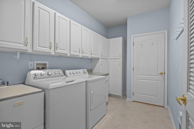 laundry area with a sink, baseboards, cabinet space, and washing machine and dryer