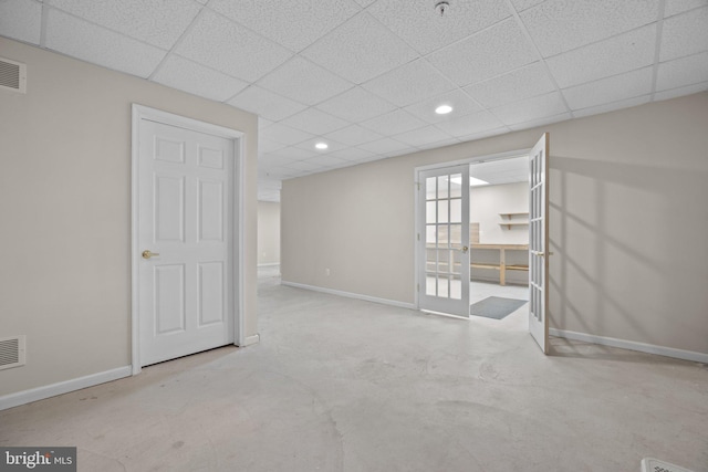 spare room featuring visible vents, concrete flooring, a paneled ceiling, and baseboards