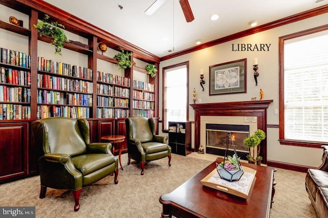 living area featuring a glass covered fireplace, carpet floors, ceiling fan, and ornamental molding