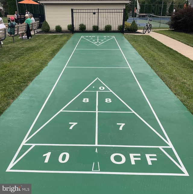 view of community featuring a lawn, shuffleboard, and fence