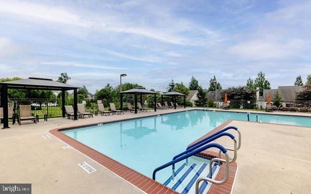 pool with a gazebo, a patio area, and fence