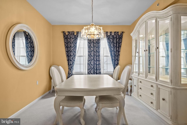 dining space with a notable chandelier, baseboards, and light carpet