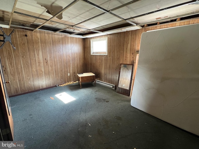 basement featuring a baseboard heating unit and wood walls