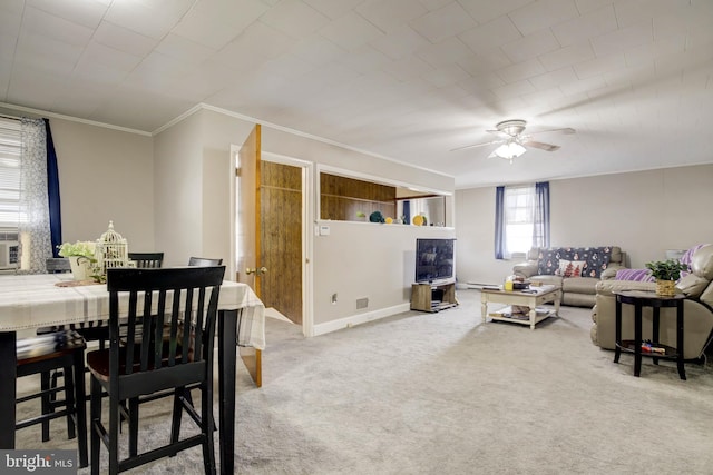 carpeted living area featuring baseboards, baseboard heating, ornamental molding, and a ceiling fan