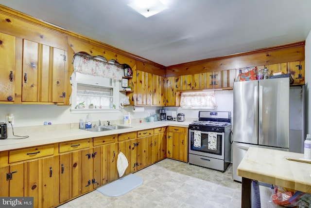 kitchen with brown cabinetry, stainless steel appliances, light countertops, and a sink