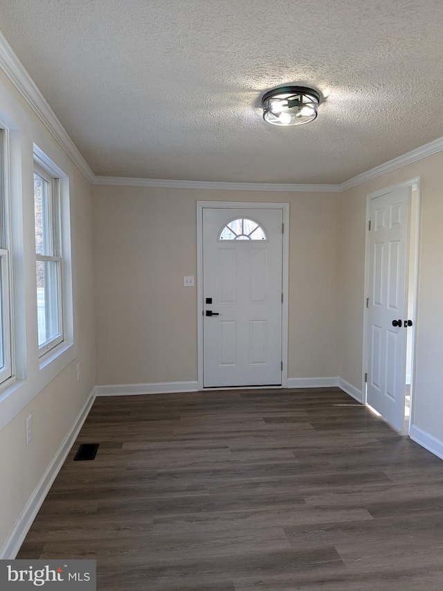 entrance foyer featuring visible vents, ornamental molding, a textured ceiling, baseboards, and dark wood-style flooring