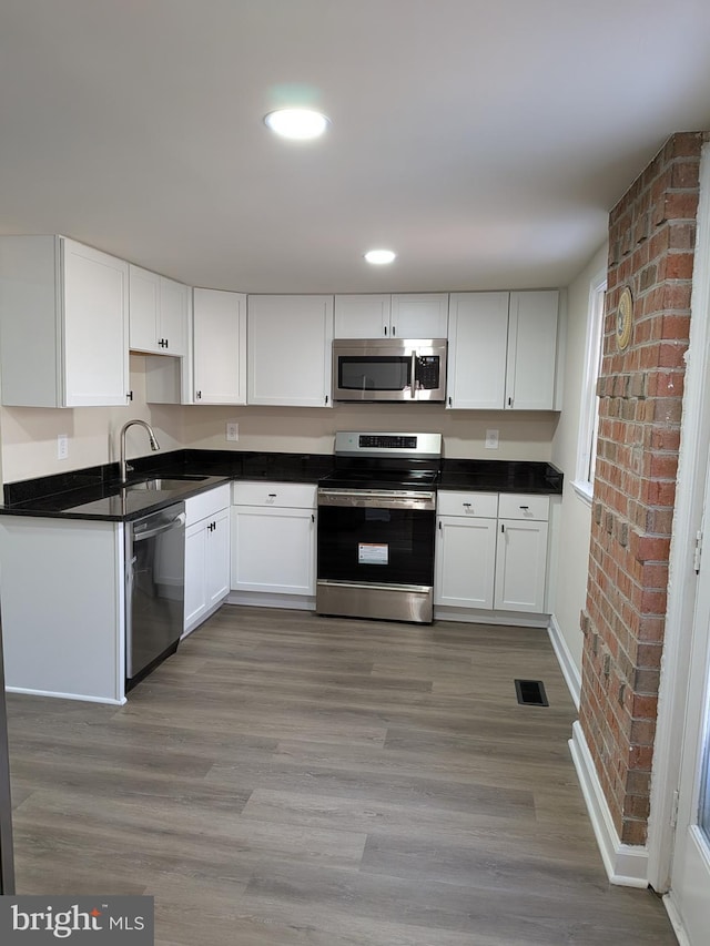 kitchen with visible vents, white cabinets, stainless steel appliances, and a sink