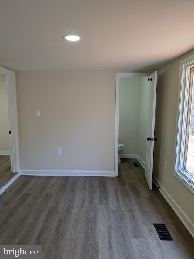 empty room featuring dark wood-type flooring, recessed lighting, visible vents, and baseboards