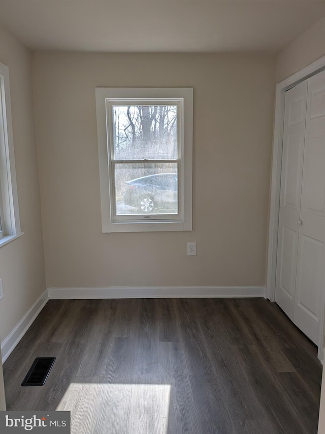 unfurnished bedroom with visible vents, baseboards, a closet, and wood finished floors