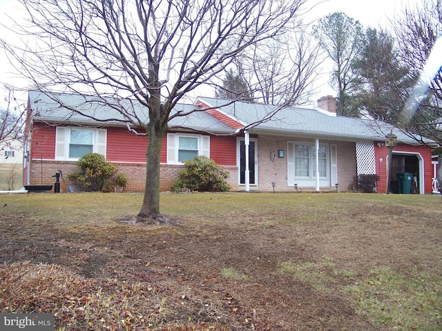 ranch-style home with brick siding, a chimney, and a front lawn