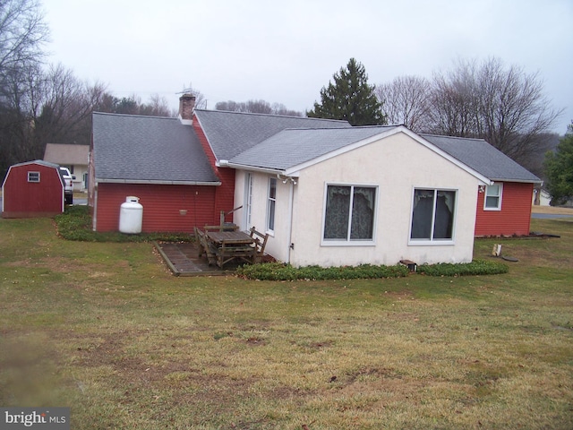 rear view of house with an outdoor structure, stucco siding, a lawn, and a chimney