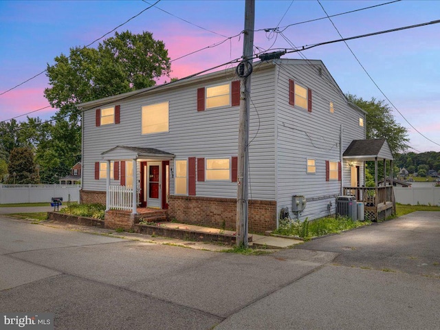 view of front of property featuring brick siding, cooling unit, and fence