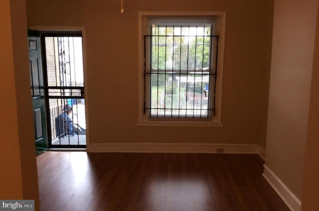 spare room featuring baseboards and wood finished floors