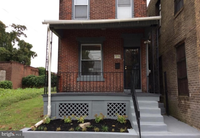 entrance to property featuring brick siding and a porch