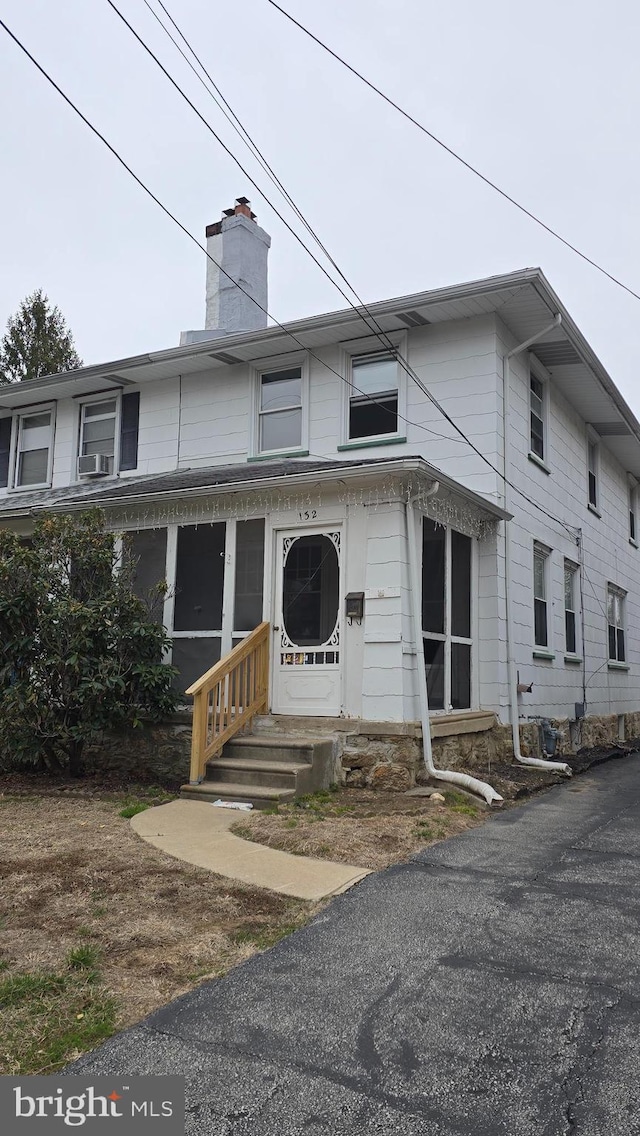 view of property featuring cooling unit, entry steps, and a chimney