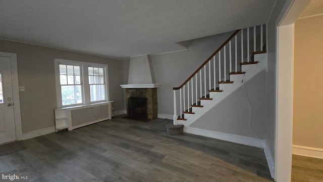 entrance foyer with baseboards, dark wood finished floors, stairs, radiator heating unit, and a fireplace