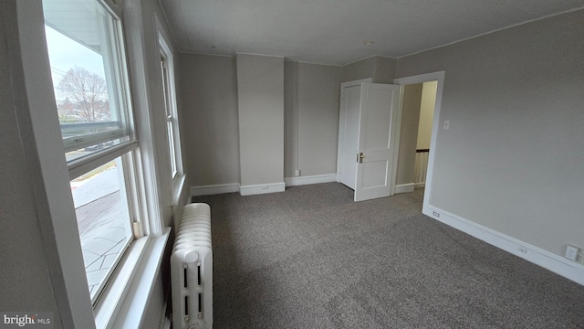 empty room featuring radiator heating unit, baseboards, and carpet floors