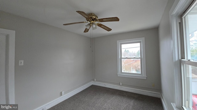 spare room with baseboards, dark colored carpet, and ceiling fan