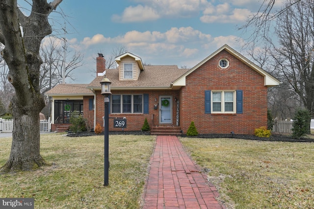 view of front of home with a front lawn, fence, brick siding, and a chimney