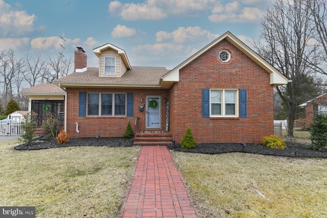 view of front of home featuring a front lawn, fence, a shingled roof, brick siding, and a chimney