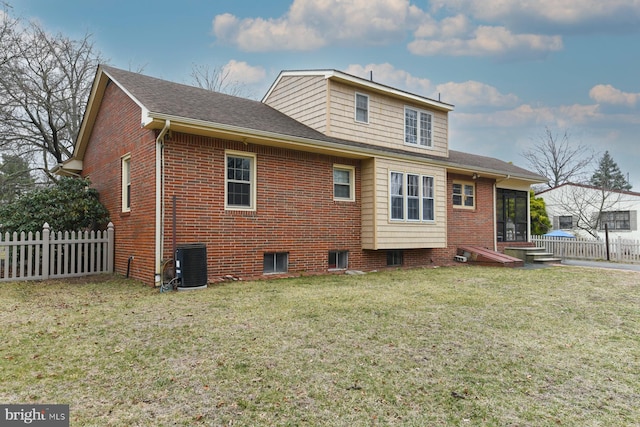 back of house with a yard, brick siding, cooling unit, and fence