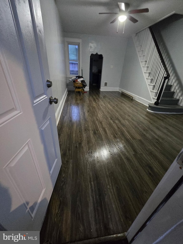 unfurnished living room featuring dark wood finished floors, baseboards, ceiling fan, and stairs