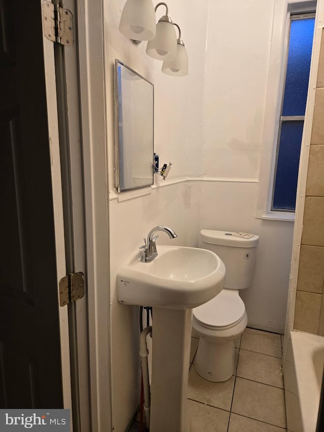 full bathroom with tile patterned floors, toilet, and a bath