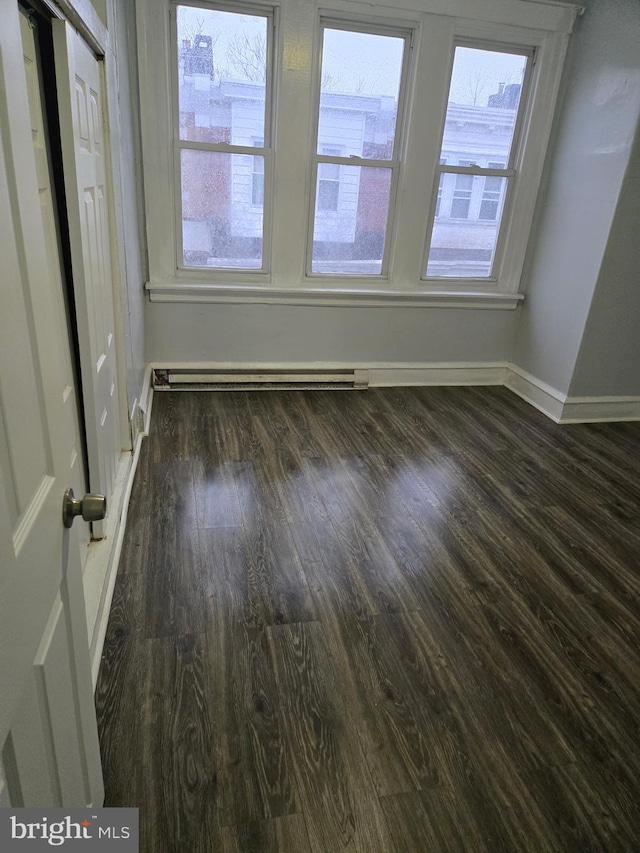 interior space with dark wood finished floors, baseboard heating, and baseboards