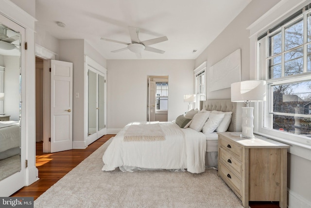 bedroom with ceiling fan, baseboards, multiple windows, and light wood-style flooring