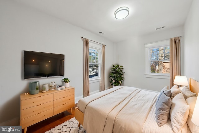 bedroom featuring visible vents, baseboards, and wood finished floors