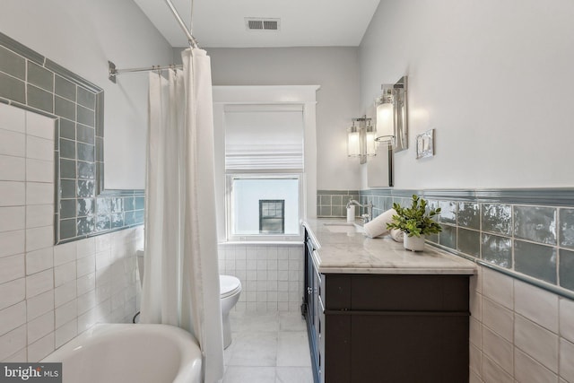 bathroom with visible vents, toilet, tile walls, and a bathing tub