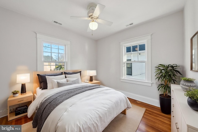 bedroom featuring ceiling fan, wood finished floors, visible vents, and baseboards