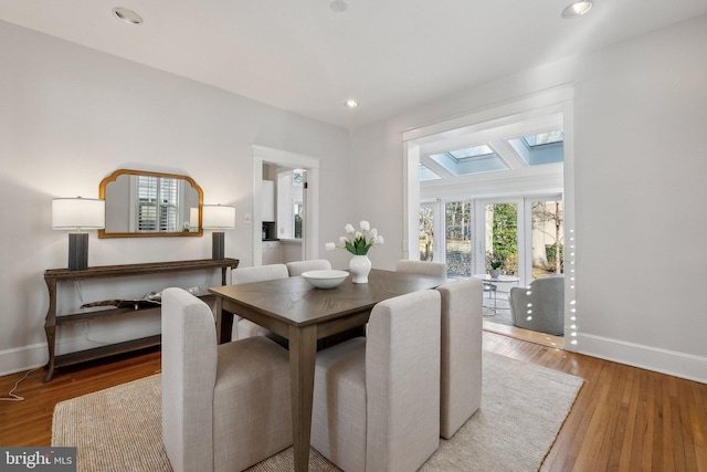 dining room with recessed lighting, baseboards, wood finished floors, and a skylight