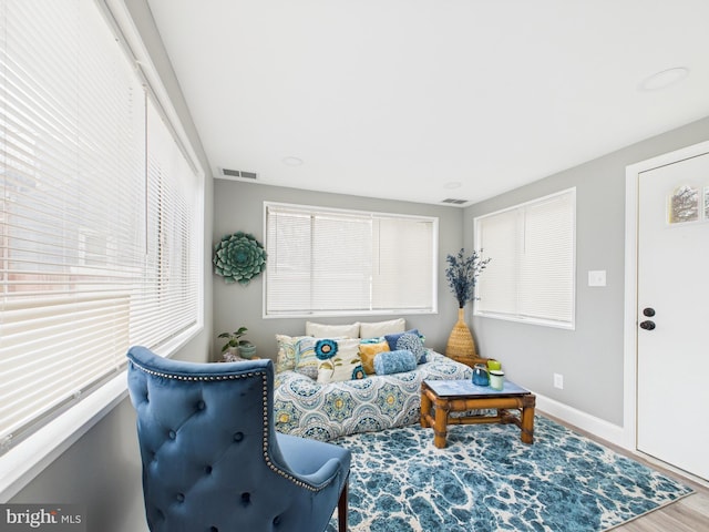 living room with visible vents, baseboards, and wood finished floors