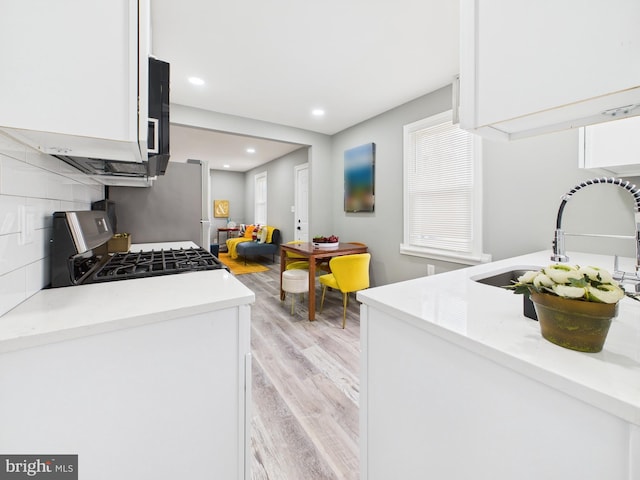 kitchen with recessed lighting, a sink, white cabinetry, light wood-type flooring, and backsplash