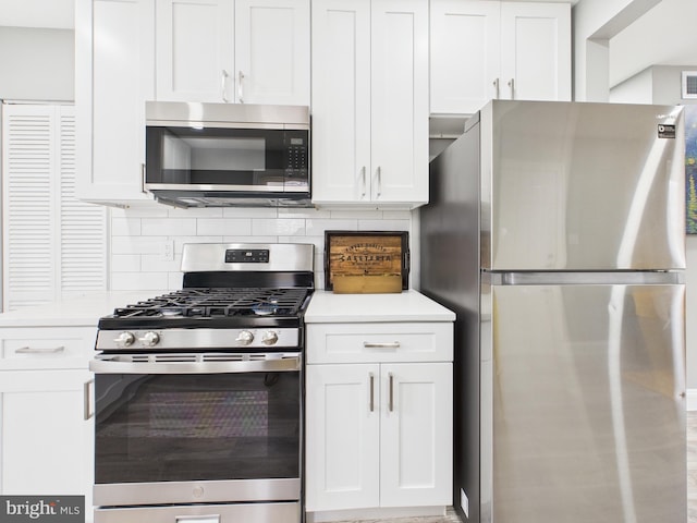 kitchen featuring tasteful backsplash, white cabinets, stainless steel appliances, and light countertops