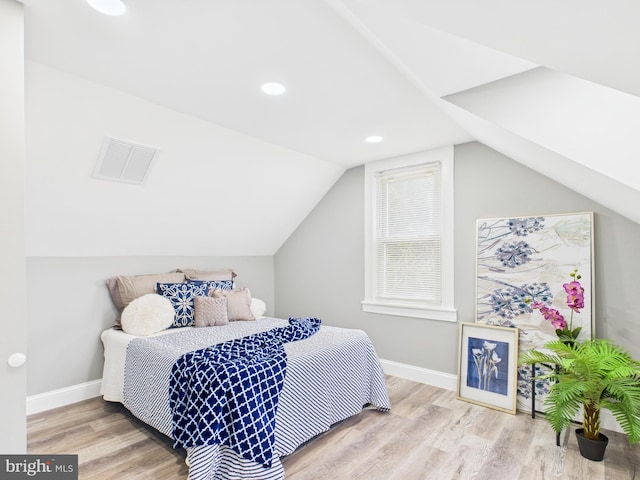 bedroom featuring visible vents, baseboards, lofted ceiling, and wood finished floors