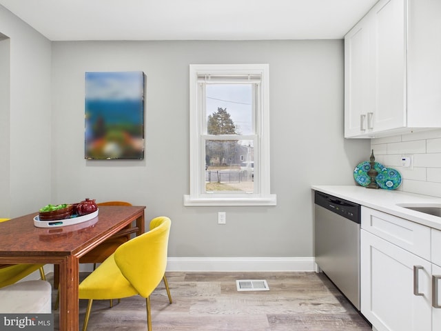 kitchen with tasteful backsplash, visible vents, dishwasher, light wood-type flooring, and white cabinetry