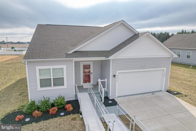 view of front of house featuring a front yard, a garage, driveway, and a shingled roof