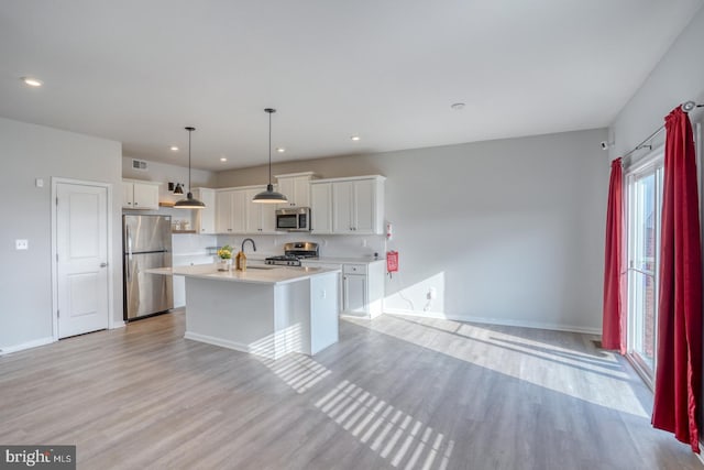 kitchen featuring a sink, appliances with stainless steel finishes, light wood-style flooring, and light countertops