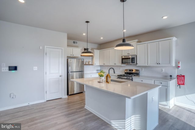 kitchen with visible vents, stainless steel appliances, light wood-style floors, white cabinetry, and a sink