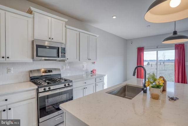 kitchen with a sink, stainless steel appliances, backsplash, and white cabinets